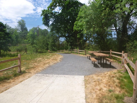 Transition from hard surface to compacted gravel – two picnic tables - bench – wood rail fence